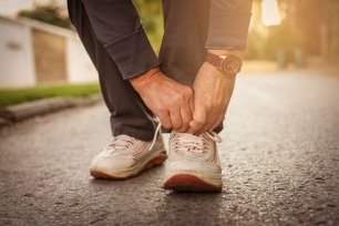 Senior woman hands tying sneakers. Close up.